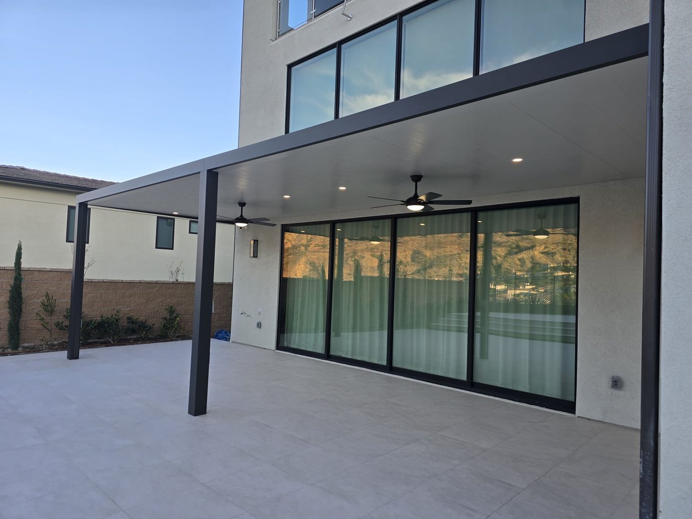 Insulated patio cover with dual ceiling fans on a modern home