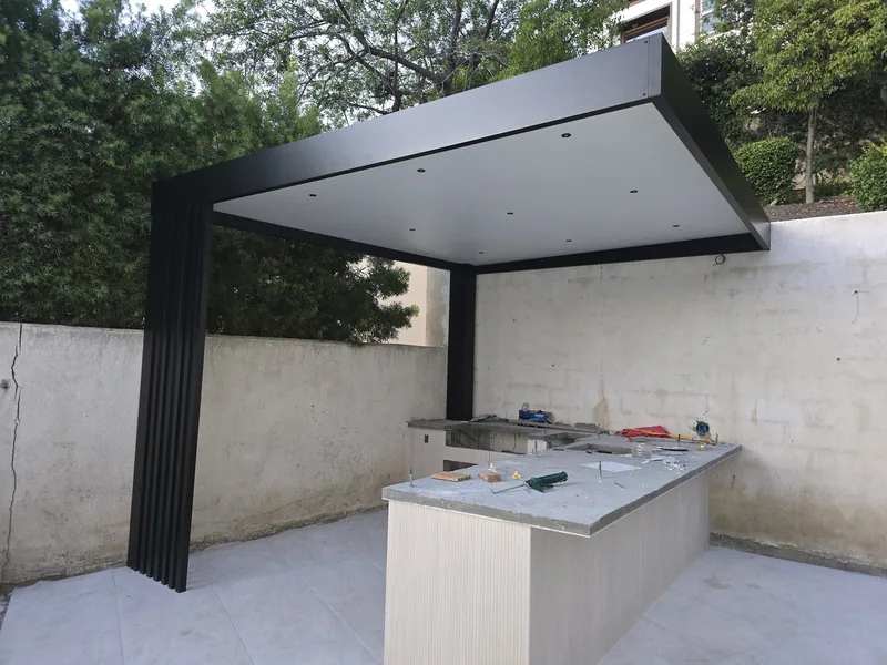 4K cantilever with white insulated roof panel and recessed downlights, over an outdoor kitchen against a garden wall