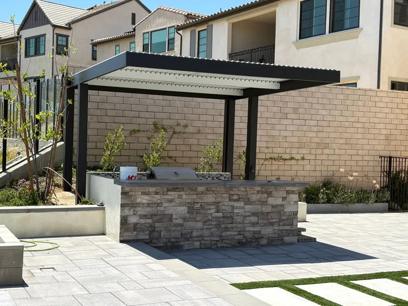 4K cantilever in espresso with white Solara adjustable louvers, over a stone-clad barbecue island
