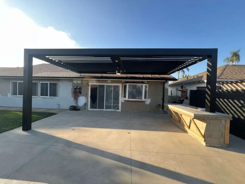 Freestanding Four Seasons louvered roof in black over a concrete patio at a single-story home, blades open