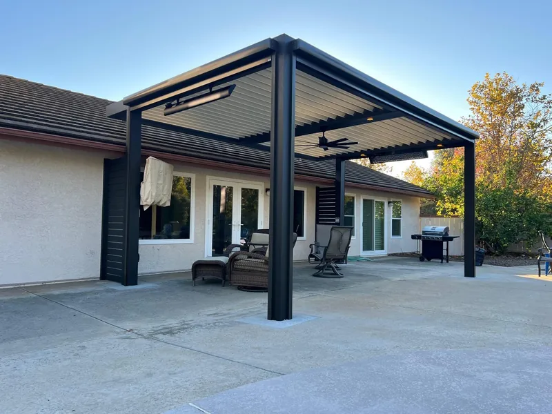 Attached Four Seasons louvered roof with black frame and latte blades, with ceiling fan, overhead heaters and integrated lighting